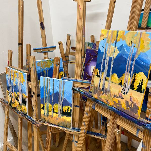 Row of acrylic paintings drying on studio easels
