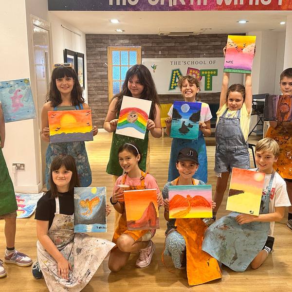 Children holding up their paintings in the studio