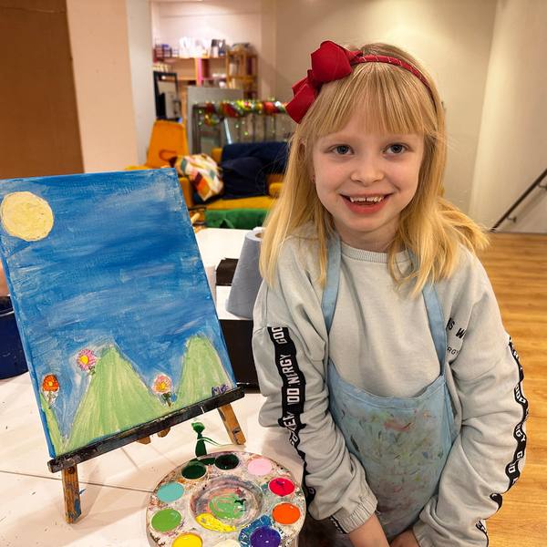 A child with a painting of a mountain landscape