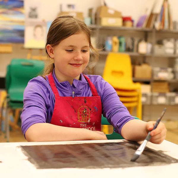 A girl painting at an art camp table
