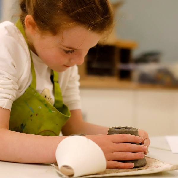 A child shaping clay at art camp